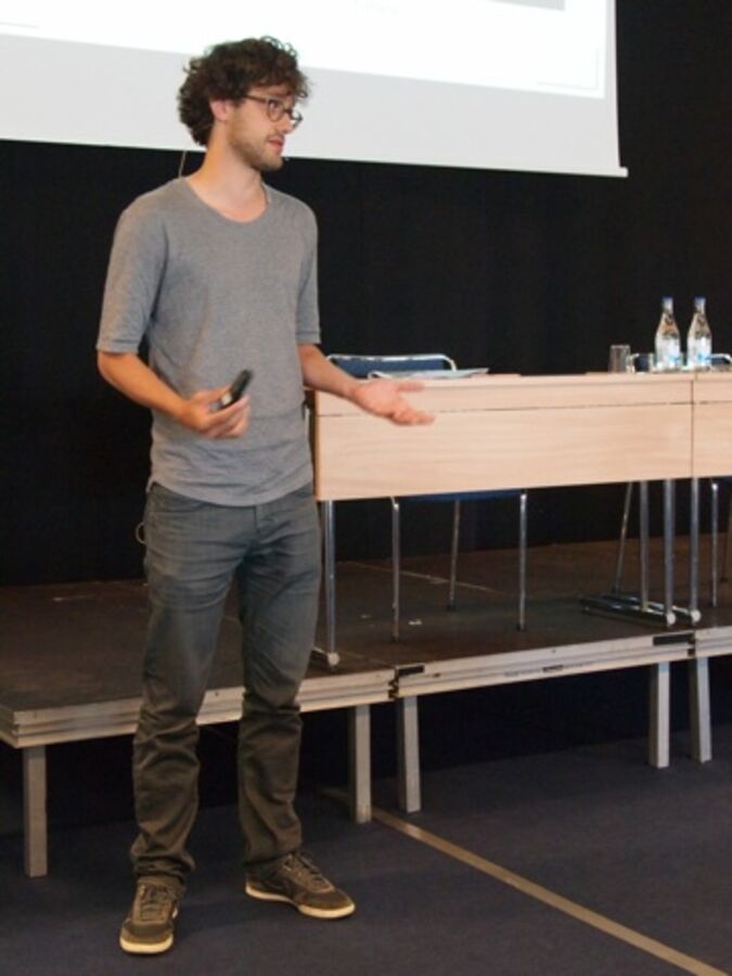 A speaker with his arms angled ninety degrees by his sides and pointing forward