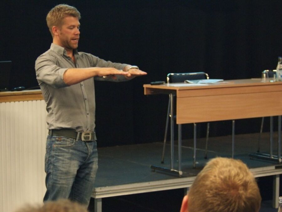 A speaker with his hands stretched out in front of him